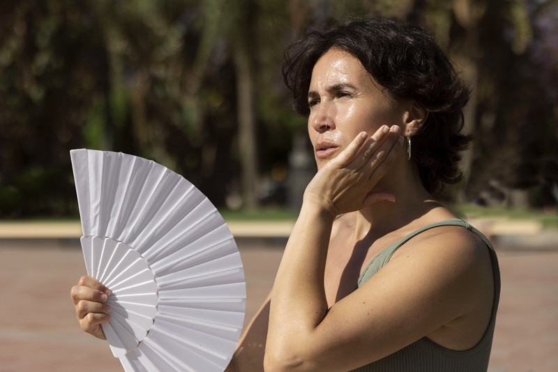 Mujer se refresca con un abanico durante un día de altas temperaturas